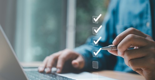 Mann hakt Checkliste am Laptop ab